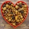 Autumn heart shape with various nuts and acorns on a wooden background