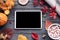 Autumn holiday background with tablet computer screen mock up on wooden table