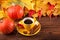 Autumn horizontal banner with yellow, red leaves, pumpkins, cup of coffee and guelder rose on brown wooden background.