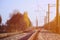 Autumn industrial landscape. Railway receding into the distance among green and yellow autumn tree