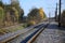 Autumn industrial landscape. Railway receding into the distance among green and yellow autumn tree