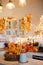 Autumn kitchen interior. Red and yellow leaves and flowers in the vase and pumpkin on light background