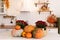 Autumn kitchen interior. Red and yellow leaves and flowers in the vase and pumpkin on light background