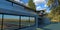 Autumn landscape. Bright blue sky with clouds. The facade of a modern office, finished with concrete and reflective windows. Long