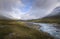 Autumn landscape in clouds and sunlight lighting up part and snow covered mountains