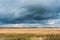 Autumn landscape with cloudy weather, large rainy clouds over a chamfered yellow field
