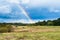 Autumn landscape with cloudy weather, large rainy clouds over a chamfered yellow field, the rainbow is in the sky