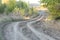 Autumn landscape with a curved road and traces of the tread of large wheels of agricultural machinery