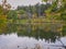 Autumn landscape with lake: Calm lakefront view of fall framed by green and red maple leaves