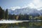 Autumn landscape of mountains covered in snow and reflected in blue lake.