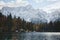 Autumn landscape of mountains covered in snow and reflected in blue lake.