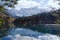 Autumn landscape of mountains covered in snow and reflected in blue lake.