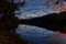 autumn landscape, nightfall and dark forest, trees near river and blue sky