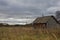 Autumn landscape with an old ruined wooden house. Old house in a field in the village on a cloudy day