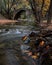 Autumn landscape with river flowing below an ancient stoned bridge