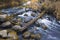 Autumn landscape with river smoothly flowing between mossy boulders