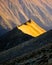 Autumn landscape showing a mountain ridge, lit from the side by the warm light of the setting sun