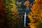 Autumn landscape in Slovenia, nature in Europe. Pericnik waterfall, Triglav Alps with orange forest, travel in Slovenia.