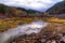 Autumn landscape. Water stream, hills and sky reflection