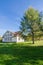 Autumn landscape with white holiday cottage, lawn and pine with blue sky background. Near the house there are bicycles