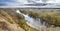 Autumn landscape - the winding river over the meadows between hills and forests