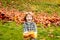 Autumn leaves. Happy child walking in autumn park. Cute boy playing with maple leaves outdoors. Toddler wears Autumn