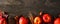 Autumn long border banner of apples, leaves, and fall decor, top view on a dark stone background