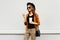 Autumn luxury look, pretty cool smiling young woman with coffee cup using smartphone walking in city, happy female model