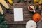 Autumn mood: present card, pumpkins and corn with yellow leaves on a wooden background