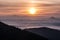 Autumn morning Carpathian mountains panorama with colorful sky, sun, misty and only few highest hills and mountain ranges above