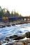 Autumn morning in Koiteli rapid, Kiiminki river. Rising sun, bright light. Bridge over the river,  flowing blue water, rocks along