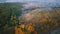 Autumn morning nature. aeriel video footage. Hill with road and colorful trees. Village on background. Cold colors of