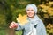 Autumn muslim woman holding maple leaf outdoors in sunny day. Beautiful arab wearing hijab girl in fall park