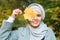 Autumn muslim woman holding maple leaf outdoors in sunny day. Beautiful arab wearing hijab girl in fall park