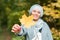 Autumn muslim woman holding maple leaf outdoors in sunny day. Beautiful arab wearing hijab girl in fall park