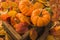 Autumn orange pumpkins, widely used for Halloween, with a background of dry and reddish leaves as well as a wooden box