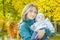 Autumn outdoor happy mother portrait holding her baby at yellow autumn shrubbery leaves background