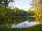 Autumn park landscape with people boating in a lake and the green foliage of the trees start to turn yellow