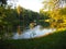 Autumn park landscape with people boating in a lake and the green foliage of the trees start to turn yellow