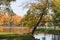 Autumn park in September in Russia, lake with red leaves and reflection, background. Beautiful autumn landscape in the park,