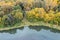 Autumn park trees with colorful fall foliage on riverbank. aerial view