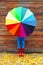 Autumn photo woman holding colorful umbrella wearing a red rubber boots over wooden background