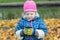 Autumn picnic portrait of little girl holding and looking at steel thermos flask cup