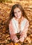 Autumn portrait of adorable smiling little girl child preteen lying in leaves