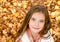 Autumn portrait of adorable smiling little girl child preteen lying in leaves in the park