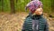 Autumn portrait of a girl in a hat and scarf. The child walks in the forest.