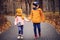 Autumn portrait of happy brother and sister walking the road in sunny park