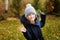 autumn portrait of happy kid girl walking in the garden in warm parka coat