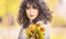 Autumn portrait of young woman with curly hair and bouquet of maple leaves