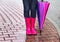 Autumn. Protection in the rain. Woman (girl) wearing pink rubber boots and has colorful umbrella.